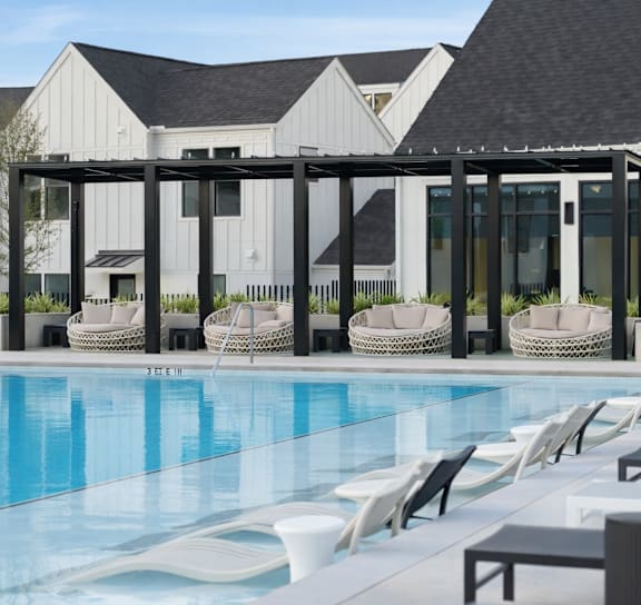 A pool area with sun loungers and a white building in the background.