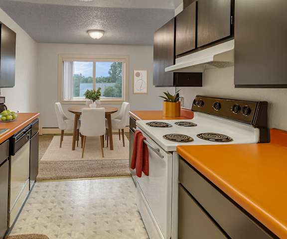 A kitchen with an orange counter top and white appliances at Arctic Sun Apartments. 