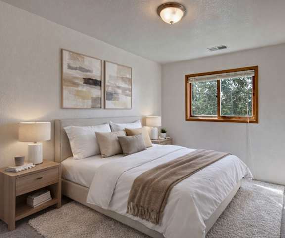 An empty carpeted bedroom with a window at the Legacy West Apartment Homes. 