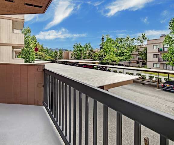 The business center with a desk with two monitors, two keyboards, and a printer, a leather couch, a meeting table with leather chairs surrounding it, overhead lighting, a ceiling fan, and a window with blinds at Susitna Apartment Homes. 