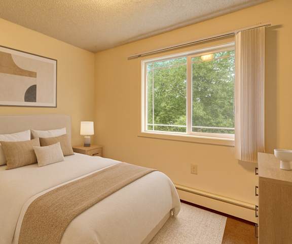 A large, empty carpeted bedroom with overhead lighting, closets, a window, and a closet at Taiga Apartment Homes. 