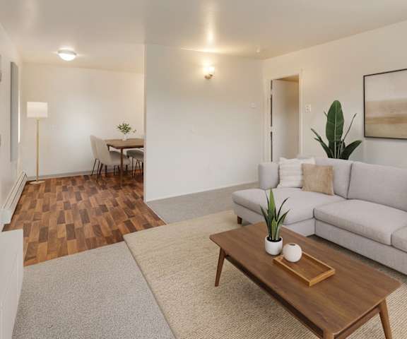 A view of the large empty living room with a window and the door at the Village at Calais Apartment Homes. 