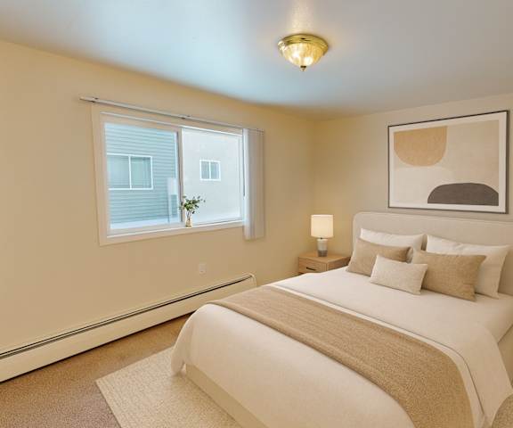A large, empty carpeted bedroom with overhead lighting and a closet at the Village at Calais Apartment Homes. 