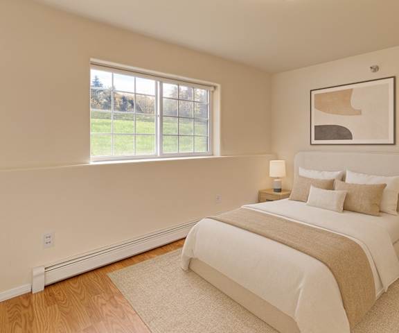 A large, empty living room with hardwood flooring and kitchen with a door to a balcony at Timber Ridge Apartment Homes. 