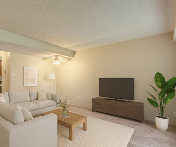 An empty living room with two windows and a kitchen with light wooden cabinets and white appliances at Lakewood Heights. 