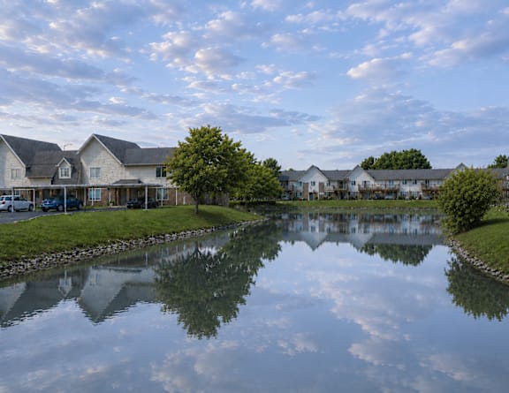 A serene lake in a residential area with houses on the other side.