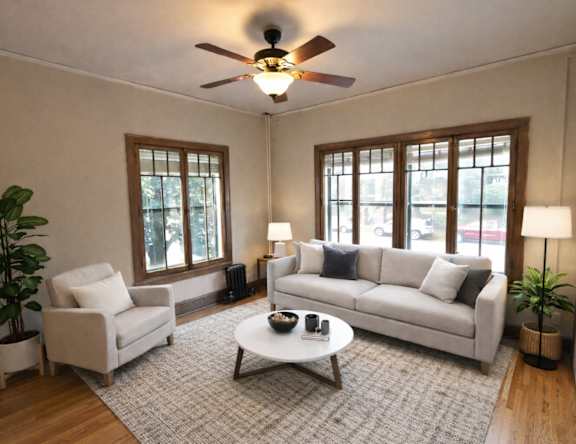 A living room with a white couch, a coffee table, and a ceiling fan.