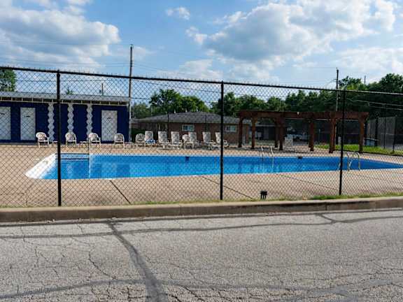 A pool surrounded by a black fence and a building in the background.