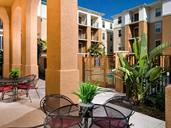 A patio with a table and chairs is surrounded by a fence and buildings.