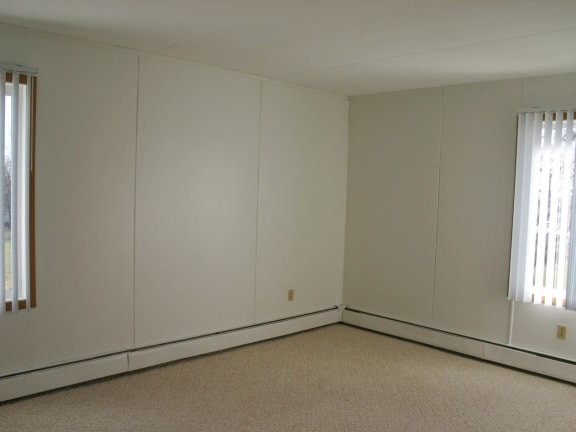 an empty room with white walls and two windows