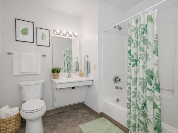 A white bathroom with a green and white shower curtain.