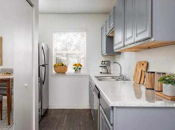 A kitchen with a refrigerator, sink, and a dining table with chairs.