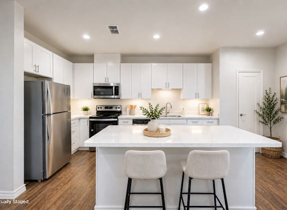 A modern kitchen with stainless steel appliances and wooden floors.