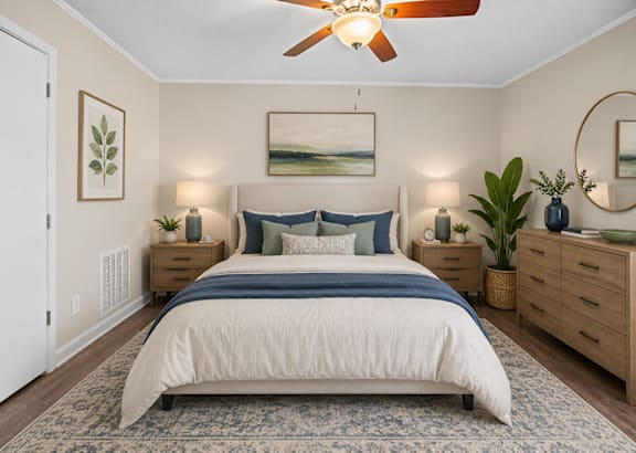 A bedroom with a large bed, a ceiling fan, and a mirror on the wall.