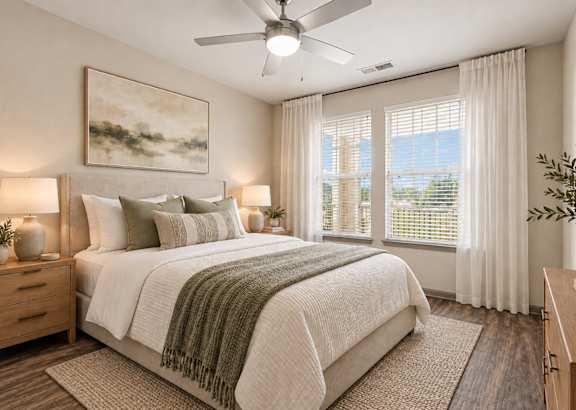 A bedroom with a bed, nightstand, and a plant.