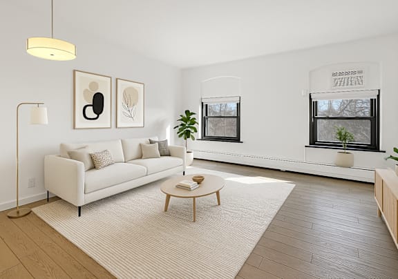 A living room with a white couch, a wooden coffee table, and two framed pictures on the wall.