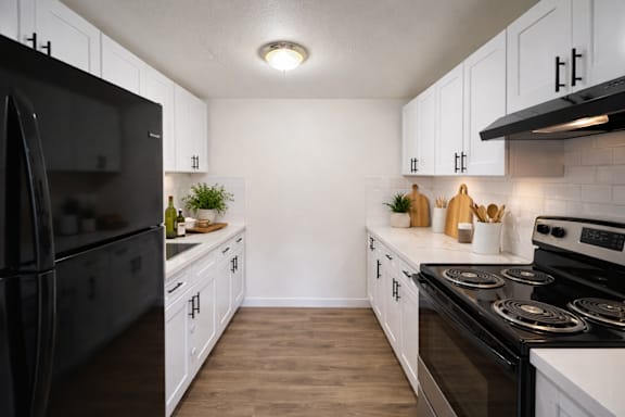 A kitchen with black appliances and white cabinets.