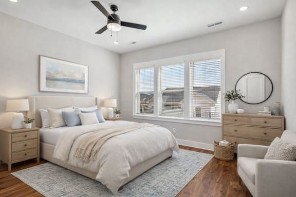 A bedroom with a large bed, a ceiling fan, and a painting on the wall.