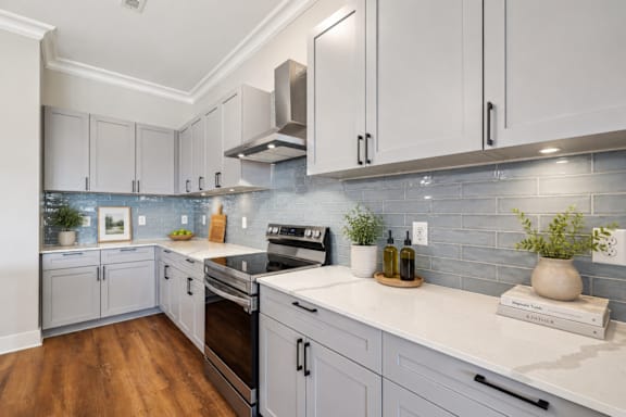 A kitchen with white cabinets and a wooden floor.