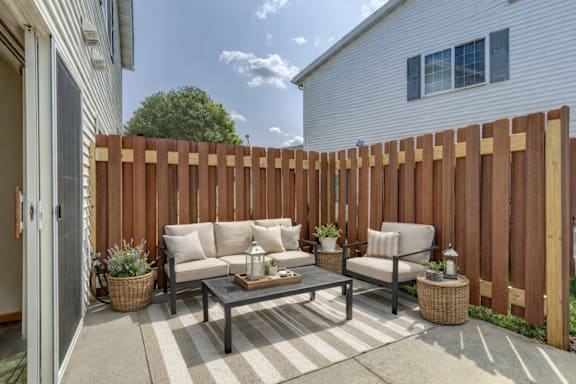 A patio with a table and chairs is surrounded by a wooden fence.