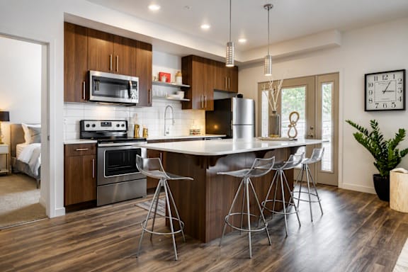 A modern kitchen with a bar stool and a clock on the wall.