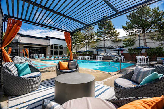 A pool area with a canopy and lounge chairs.