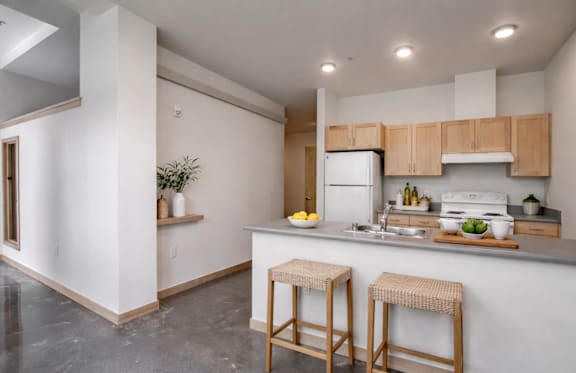 A kitchen with a white fridge and wooden bar stools.