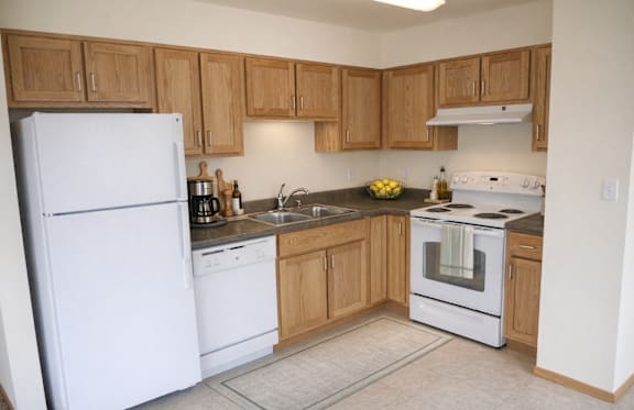 A kitchen with white appliances and wooden cabinets.