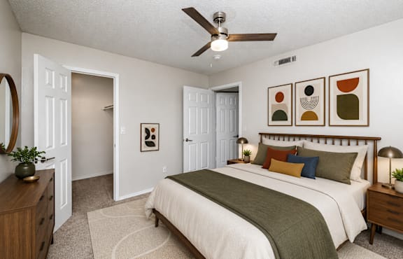 A bedroom with a bed, dresser, and ceiling fan.