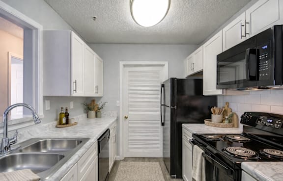 A kitchen with black appliances and white cabinets.