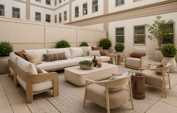 A patio with a white couch, chairs, and a coffee table.