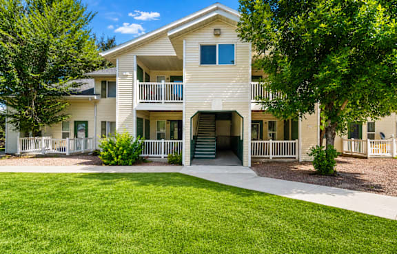 A white two-story apartment building with a green lawn in front.