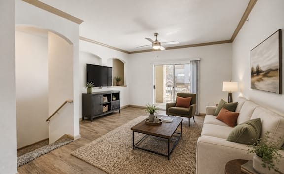 A living room with a white couch, a coffee table, a television, and a rug.