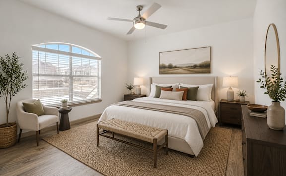 A bedroom with a large bed, a chair, a window, and a painting on the wall.