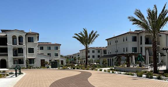 A sunny day at a residential complex with palm trees and a clear blue sky.