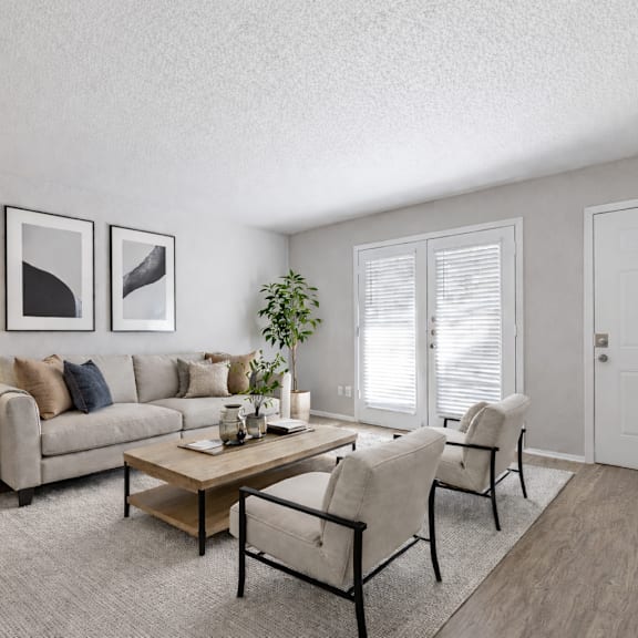 A living room with a grey couch, a coffee table, and two chairs.