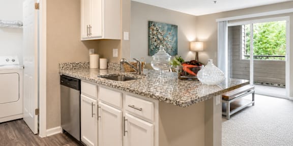 A kitchen with a granite countertop and white cabinets.