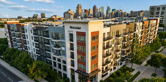 A street view of a multi-story building with cars parked on the side of the road.