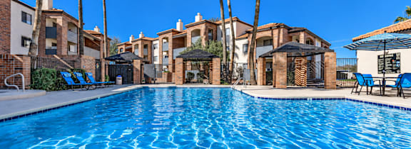 A swimming pool surrounded by a poolside area and buildings.