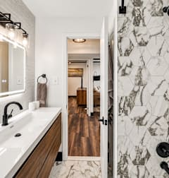 A bathroom with a marble tile shower and a wooden vanity.