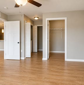 A white bathroom with wooden floors and a white toilet.at Hawthorne Pointe, Bondurant, 50035