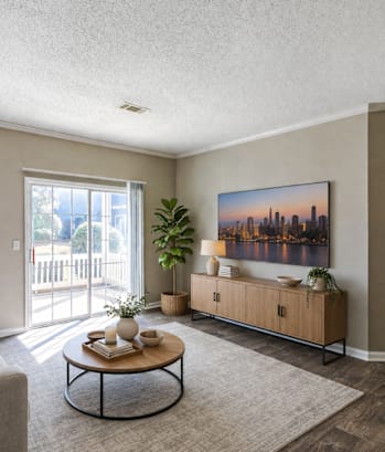 A living room with a grey couch, a coffee table, a plant, and a painting on the wall.