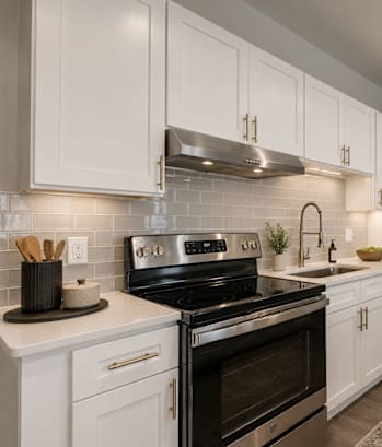 A modern kitchen with white cabinets and a black stove top oven.