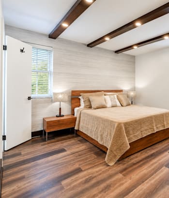 A bedroom with a large bed and wooden floors.