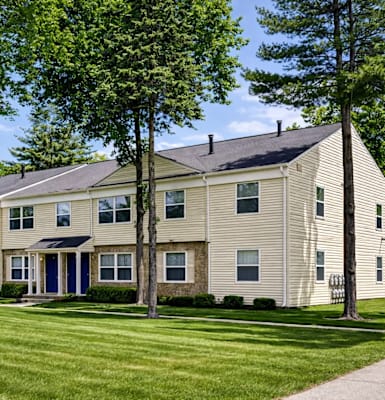 A beige house with a black roof and a blue door.