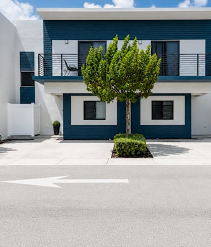 A white and blue building with a tree in front.