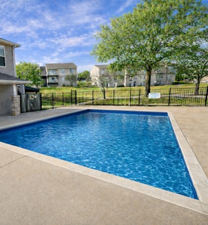 A residential house with a blue door and a pool in the backyard.