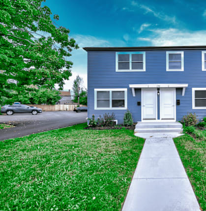 a blue house with a lawn and sidewalk in front of it