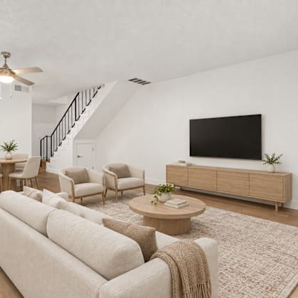 A living room with a beige couch, a coffee table, and a flat-screen TV.