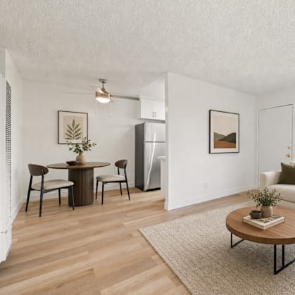 A living room with a white couch, a coffee table, and a dining table with chairs.